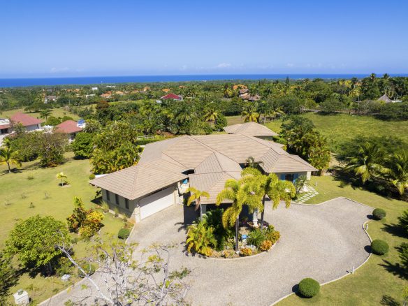 buyDRproperty Spacious villa with manicured lawn and ocean view under clear blue sky Sosua Real Estate