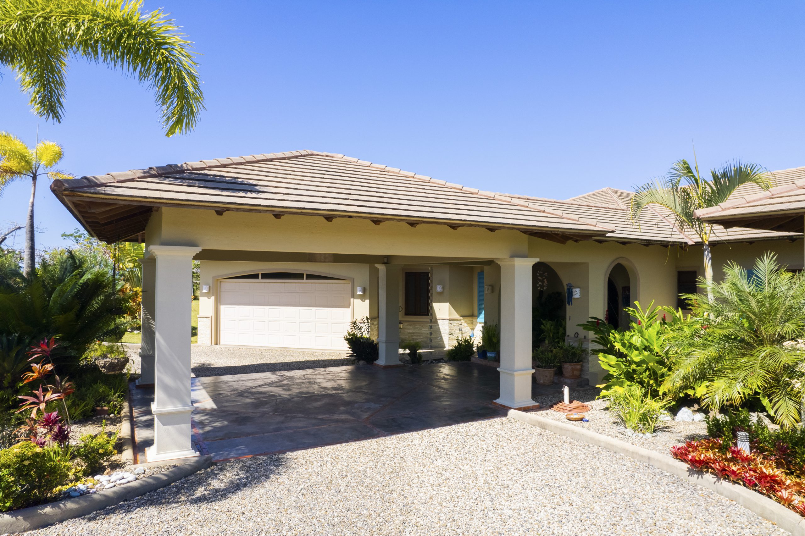 buyDRproperty Tropical villa with a spacious driveway surrounded by lush greenery Sosua Real Estate