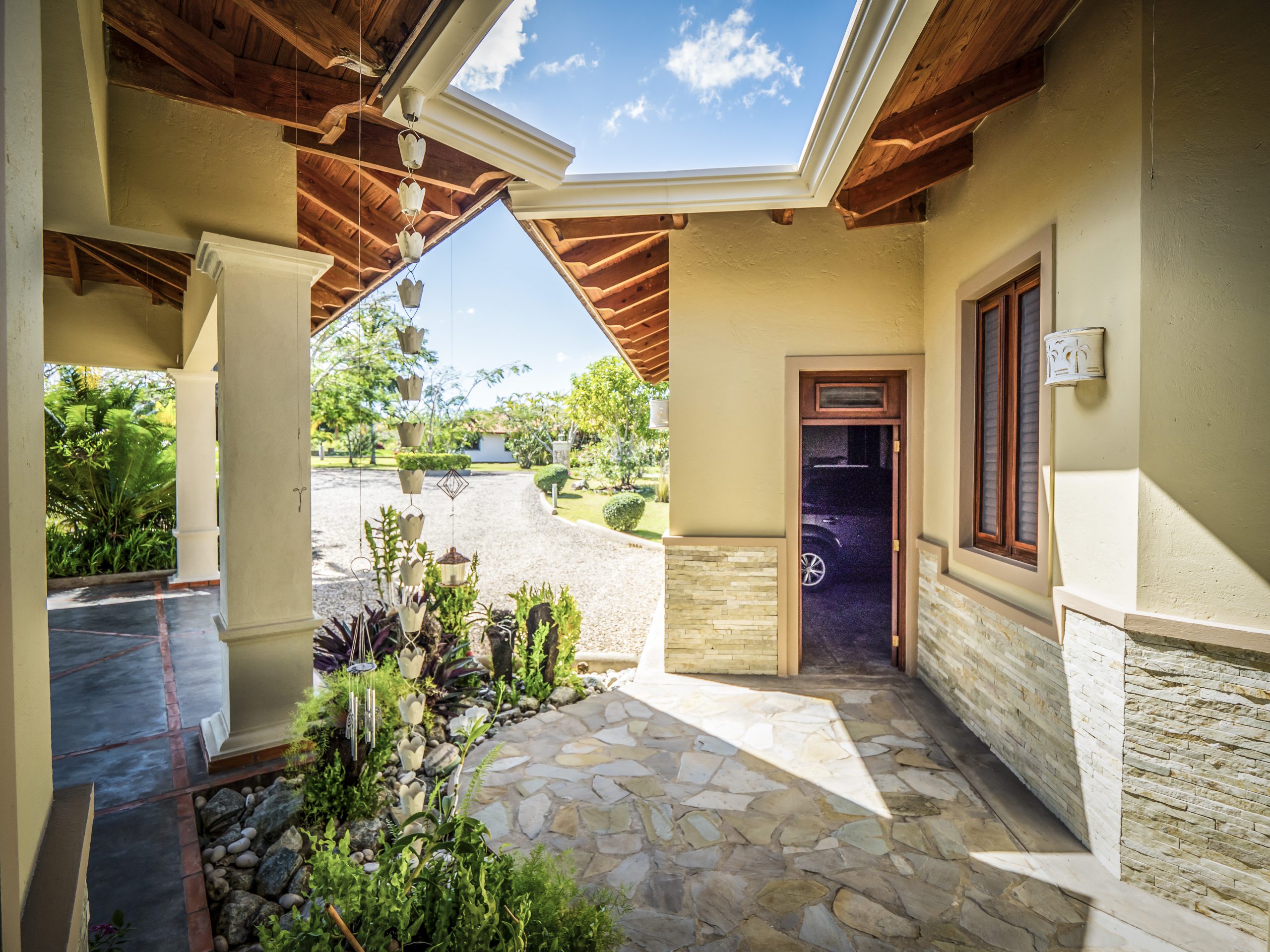 buyDRproperty Sunny patio entrance with stone flooring and garden plants Sosua Real Estate