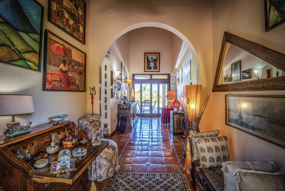buyDRproperty Colorful, art-filled hallway with arched entry and sunlight at the end Sosua Real Estate
