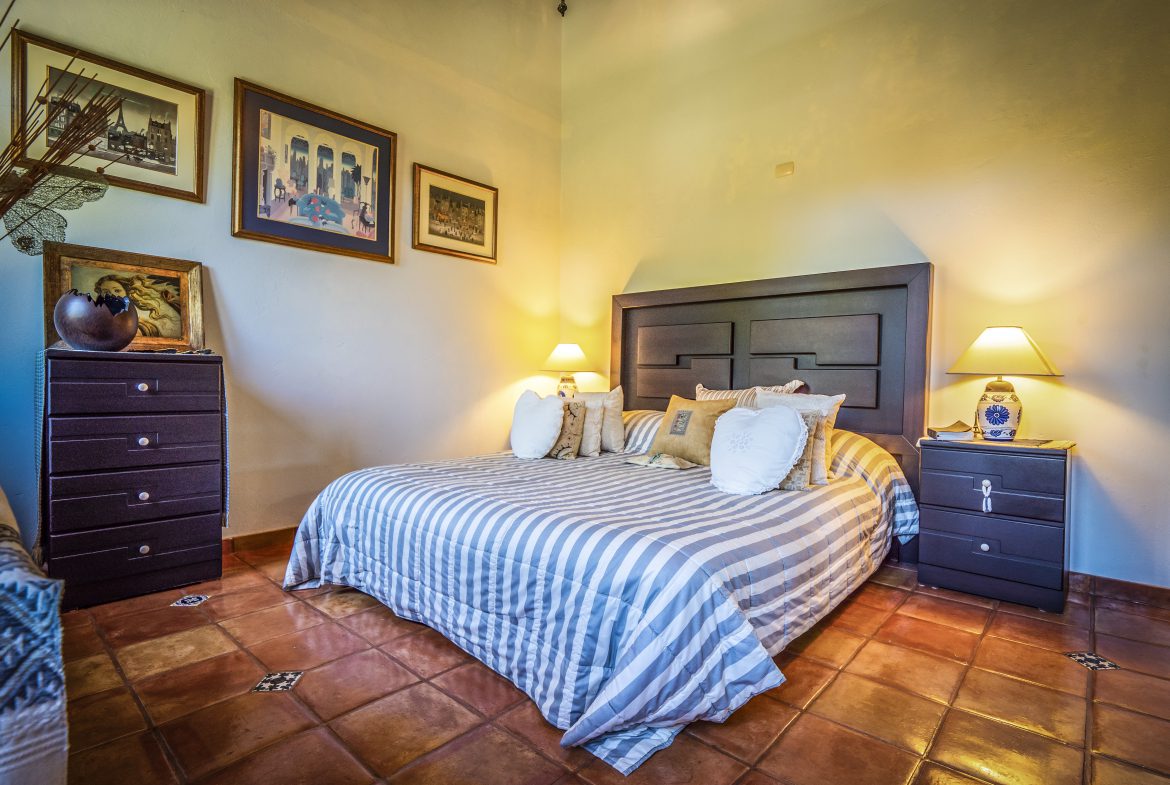 buyDRproperty Cozy bedroom with striped bedding, bedside lamps, and framed art on walls Sosua Real Estate