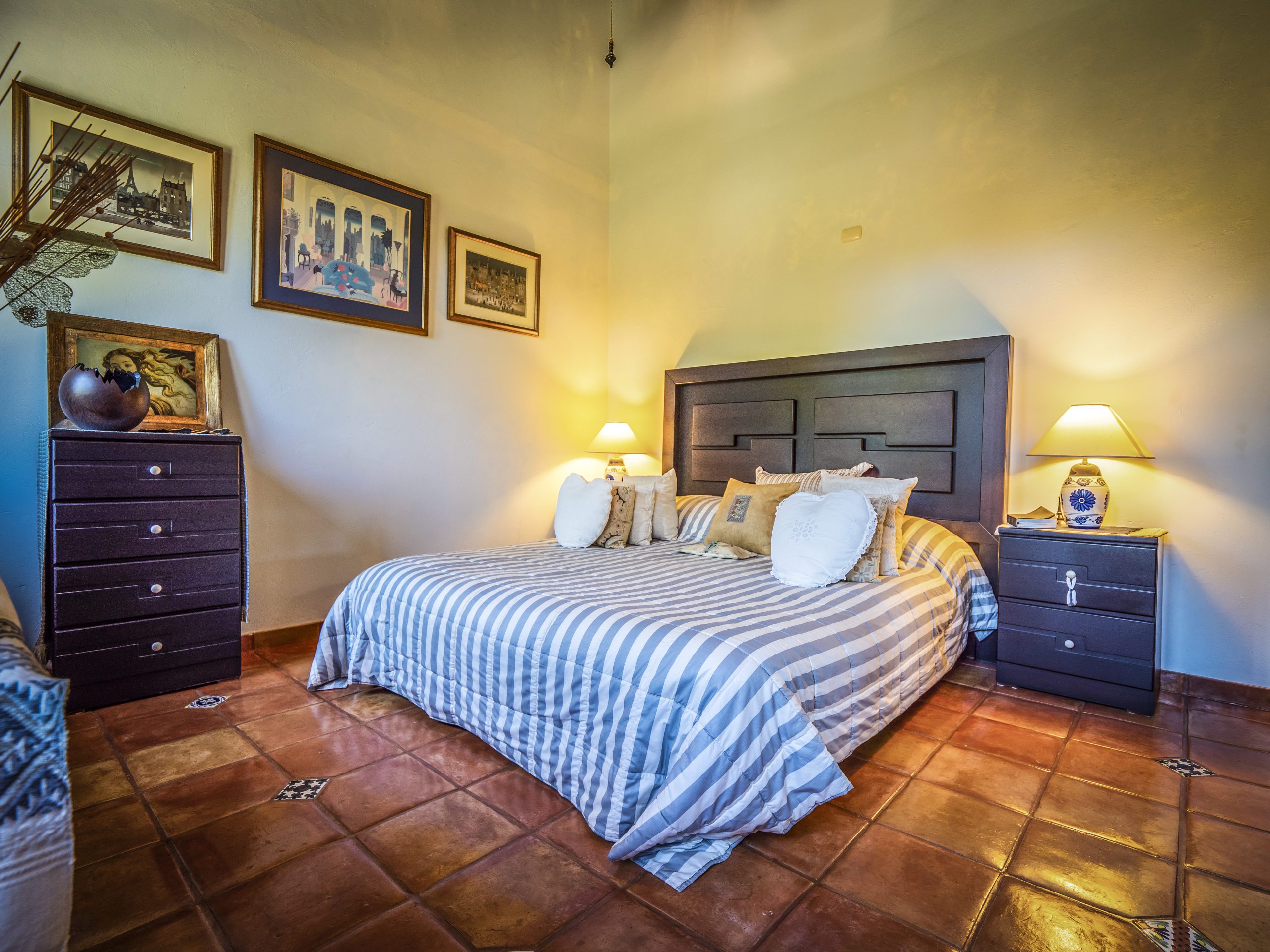 buyDRproperty Cozy bedroom with striped bedding, bedside lamps, and framed art on walls Sosua Real Estate