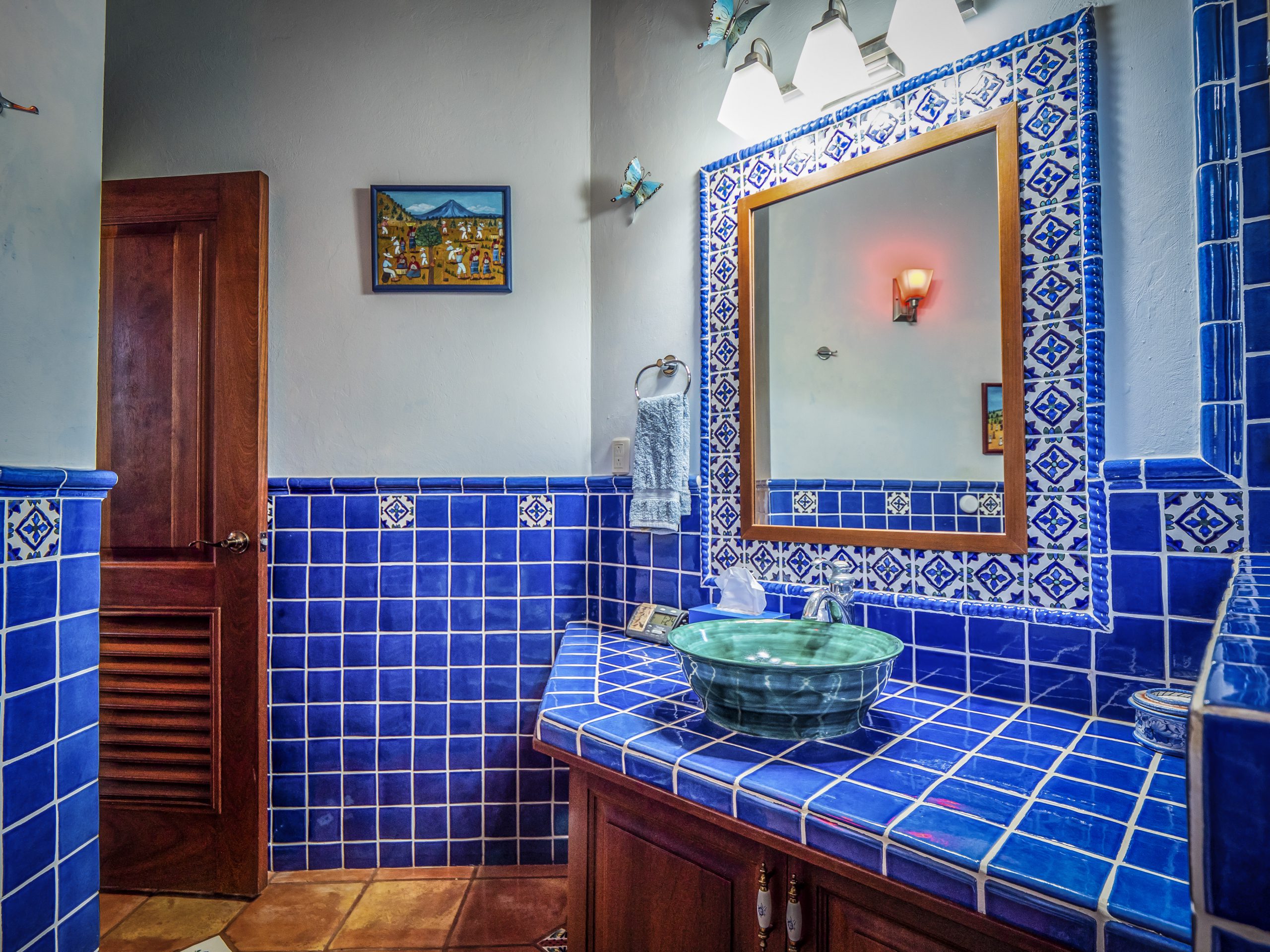 buyDRproperty Blue-tiled bathroom with decorative mirror and green sink Sosua Real Estate