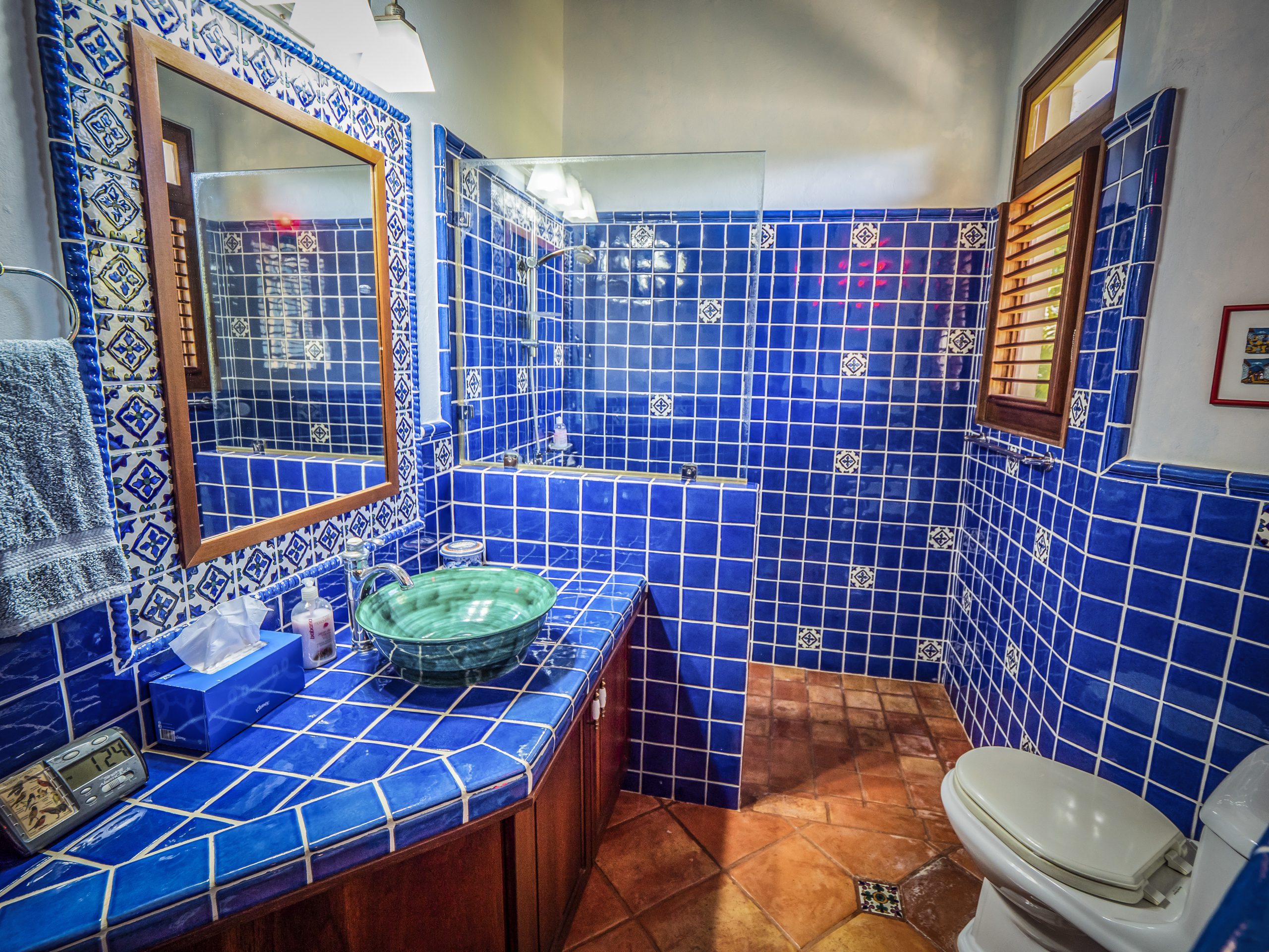buyDRproperty Blue tiled bathroom with a glass sink and wooden accents Sosua Real Estate