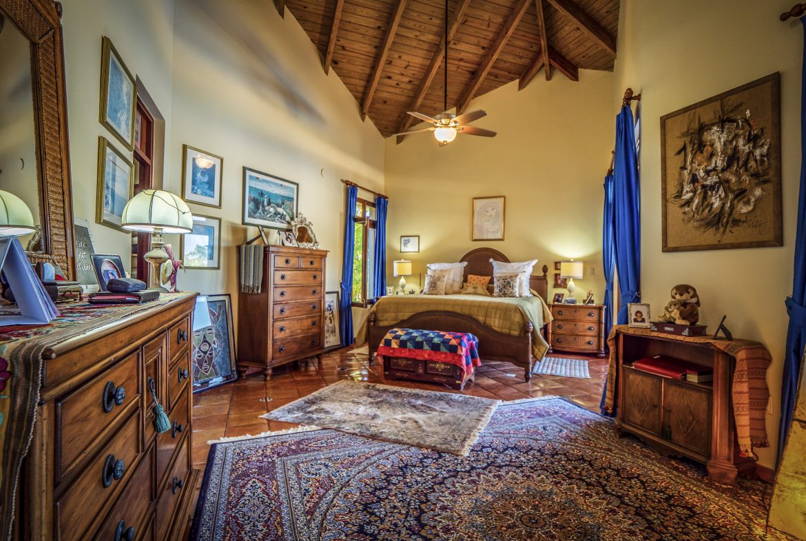 buyDRproperty Cozy bedroom with high ceiling, ornate rugs, wood furniture, and warm lighting Sosua Real Estate