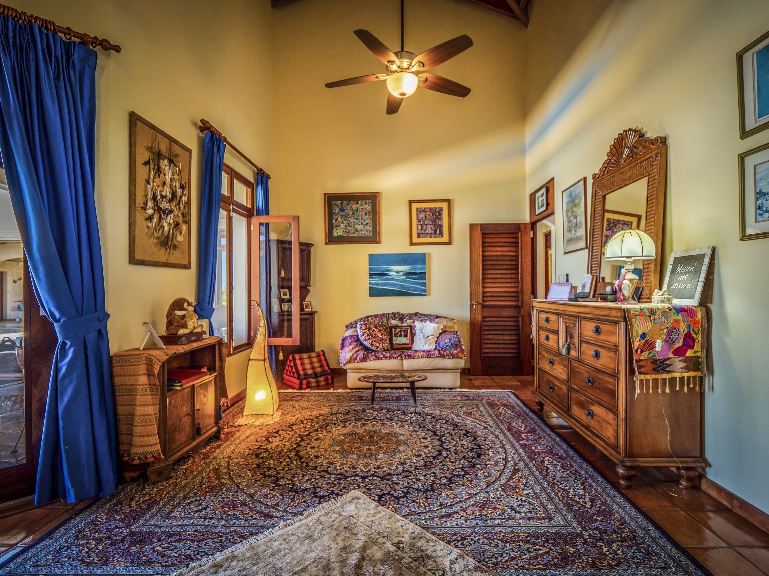 buyDRproperty Cozy living room with blue curtains, ornate rug, and ceiling fan Sosua Real Estate