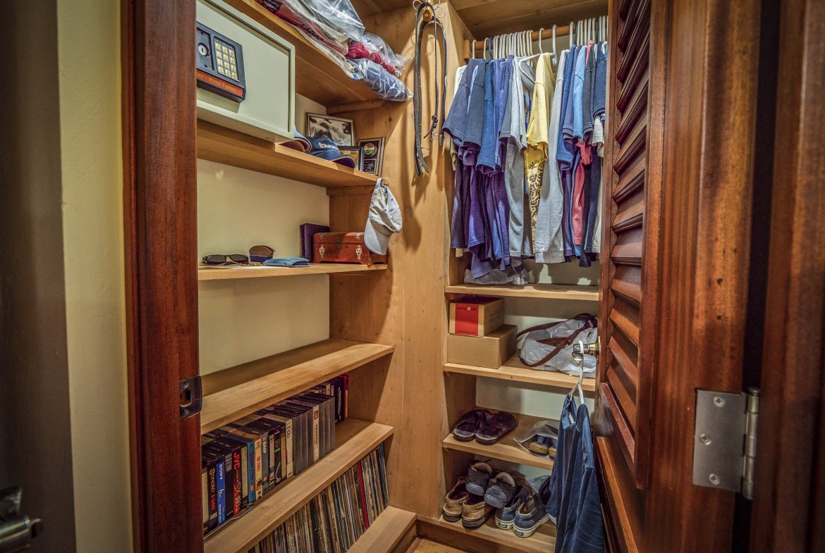 buyDRproperty Organized wooden closet with clothes, books, and folded towels Sosua Real Estate