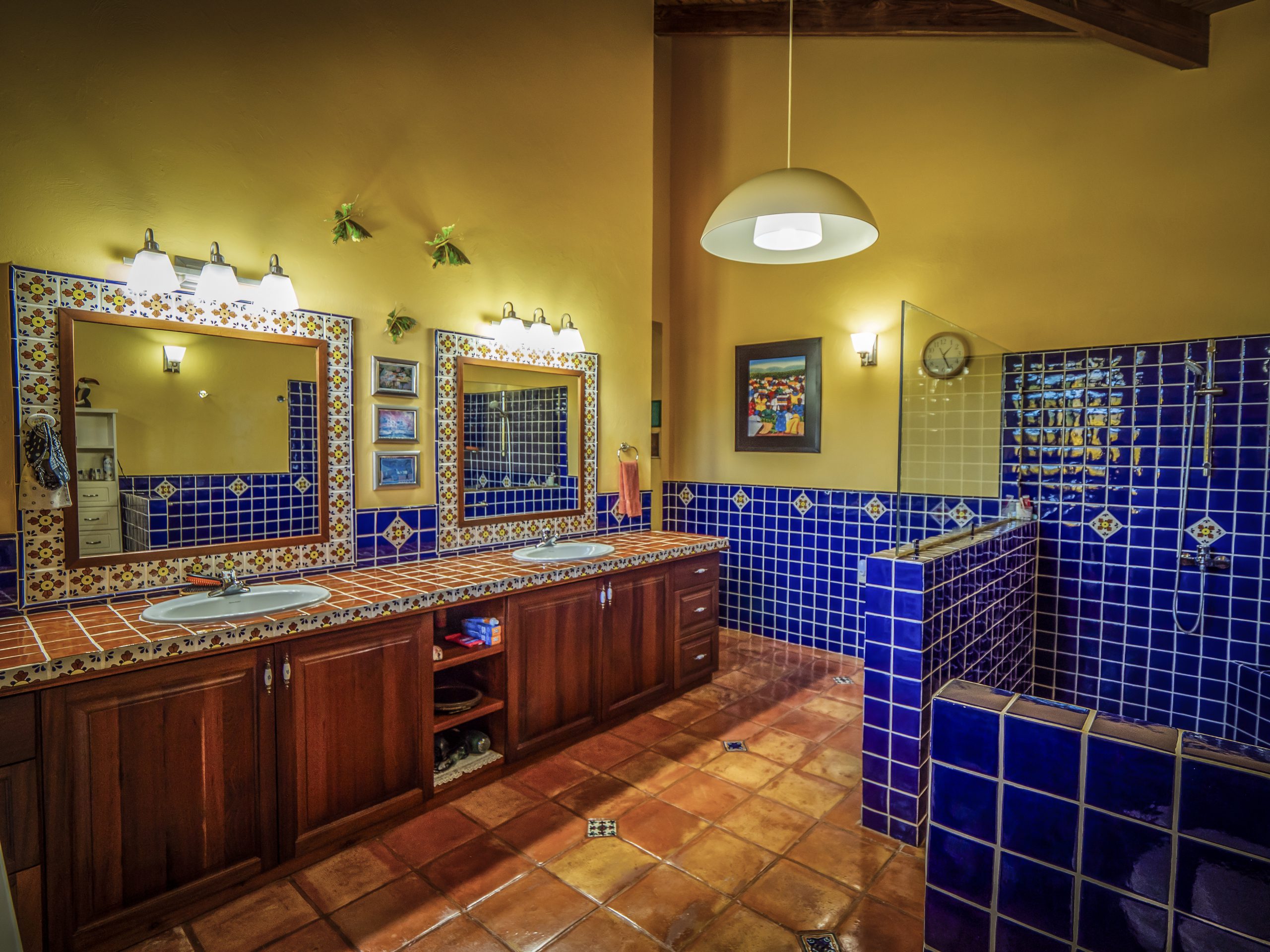 buyDRproperty Rustic bathroom with blue tiles and wooden cabinets under warm lighting Sosua Real Estate
