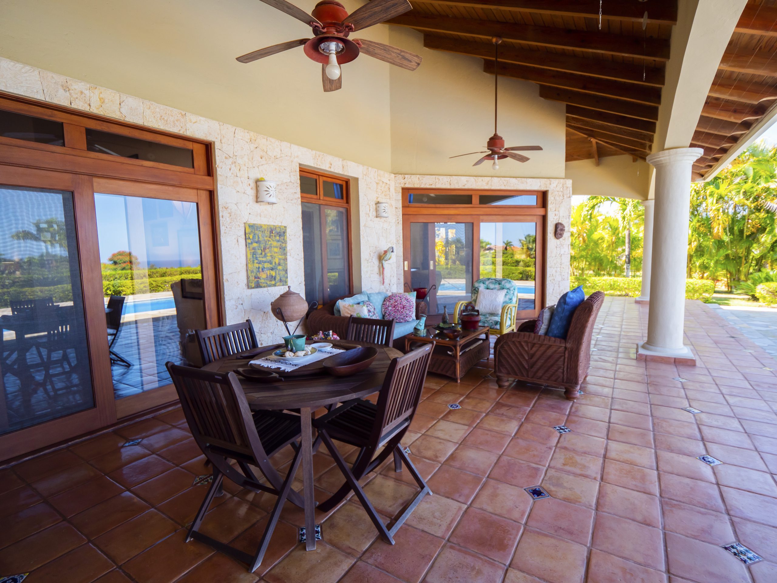 buyDRproperty Patio with wooden furniture and ceiling fans overlooking lush greenery Sosua Real Estate