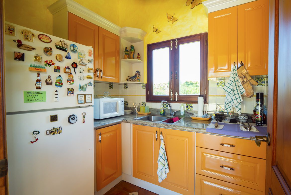 buyDRproperty Bright kitchen with yellow cabinets, window view, and decorated fridge Sosua Real Estate