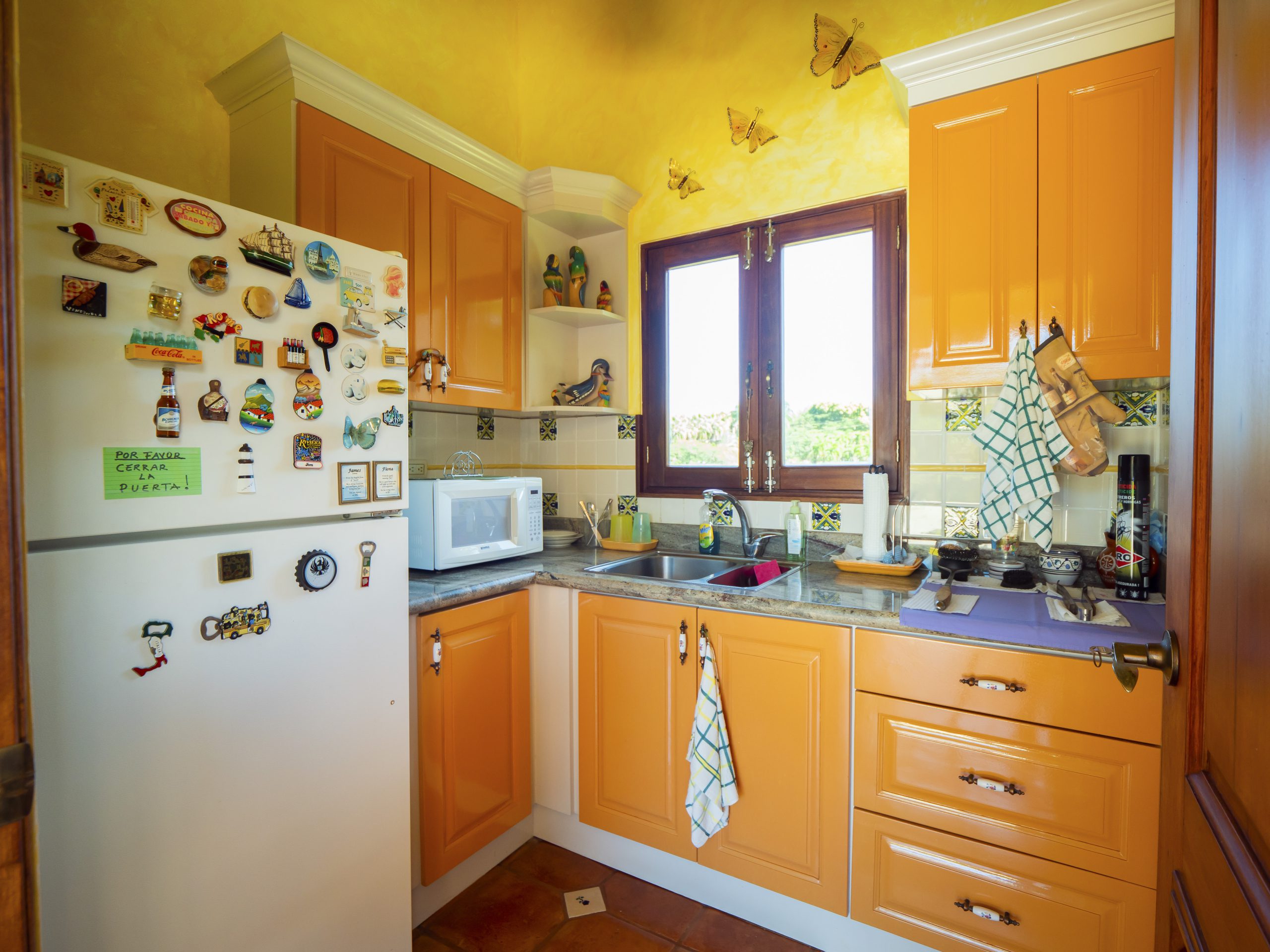 buyDRproperty Bright kitchen with yellow cabinets, window view, and decorated fridge Sosua Real Estate