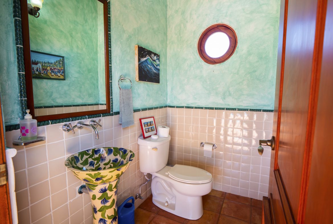 buyDRproperty Colorful bathroom with unique sink, decorative tiles, and round window. Bathroom design inspiration. Sosua Real Estate