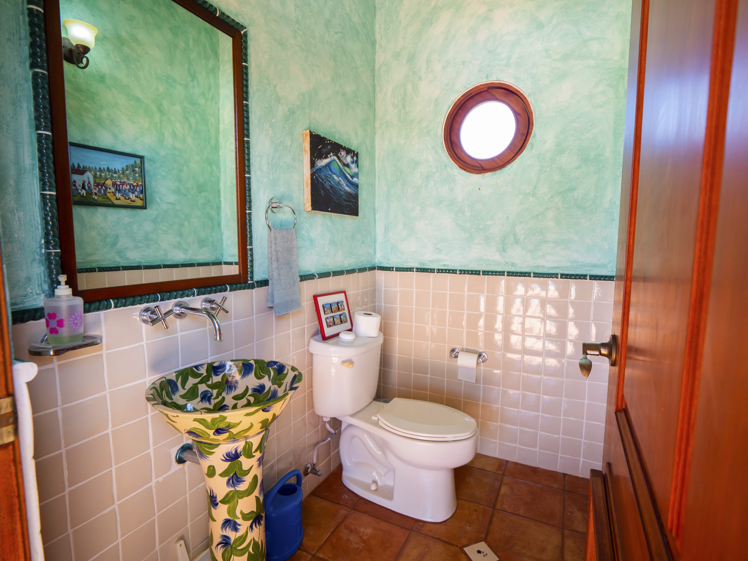 buyDRproperty Colorful bathroom with unique sink, decorative tiles, and round window. Bathroom design inspiration. Sosua Real Estate