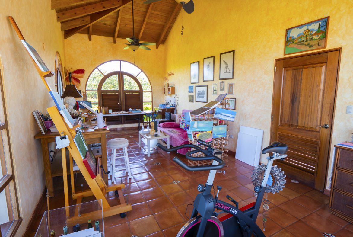 buyDRproperty Colorful art studio with easel, paintings, and exercise bike Sosua Real Estate