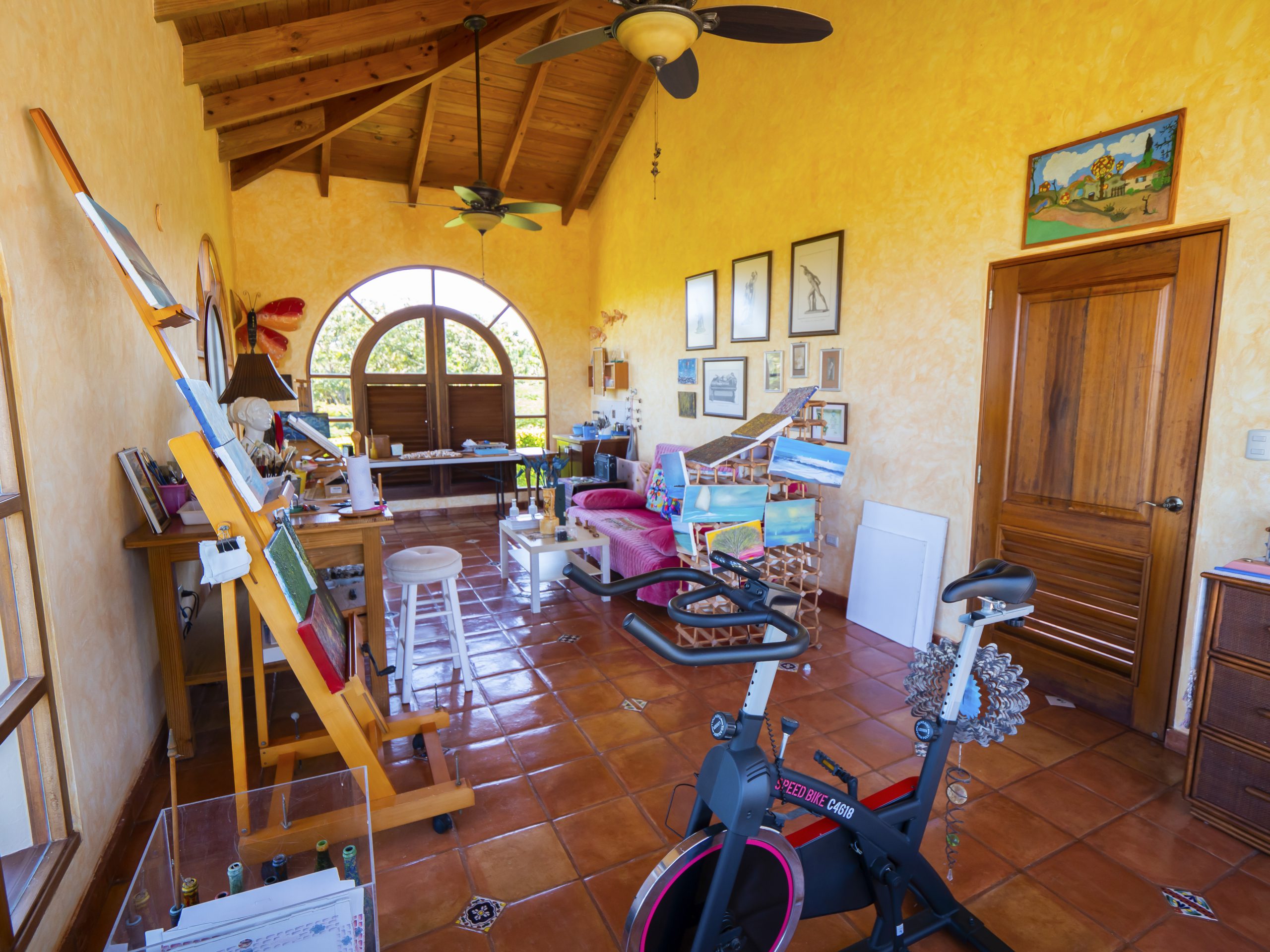 buyDRproperty Colorful art studio with easel, paintings, and exercise bike Sosua Real Estate