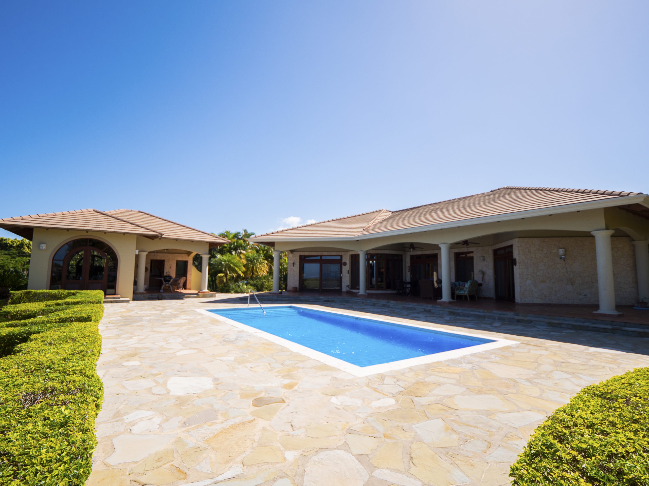 buyDRproperty Spacious villa with a blue swimming pool under a clear sky Sosua Real Estate