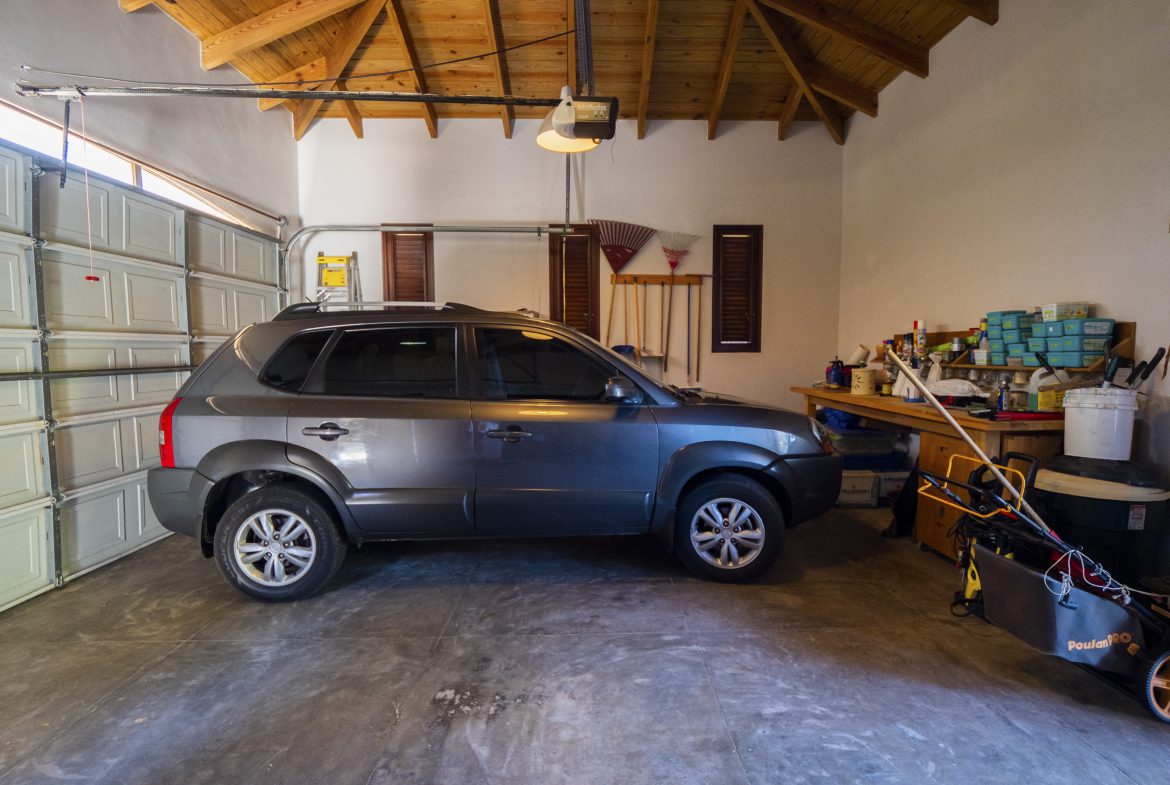 buyDRproperty Gray SUV parked inside a well-organized garage with wooden ceiling Sosua Real Estate