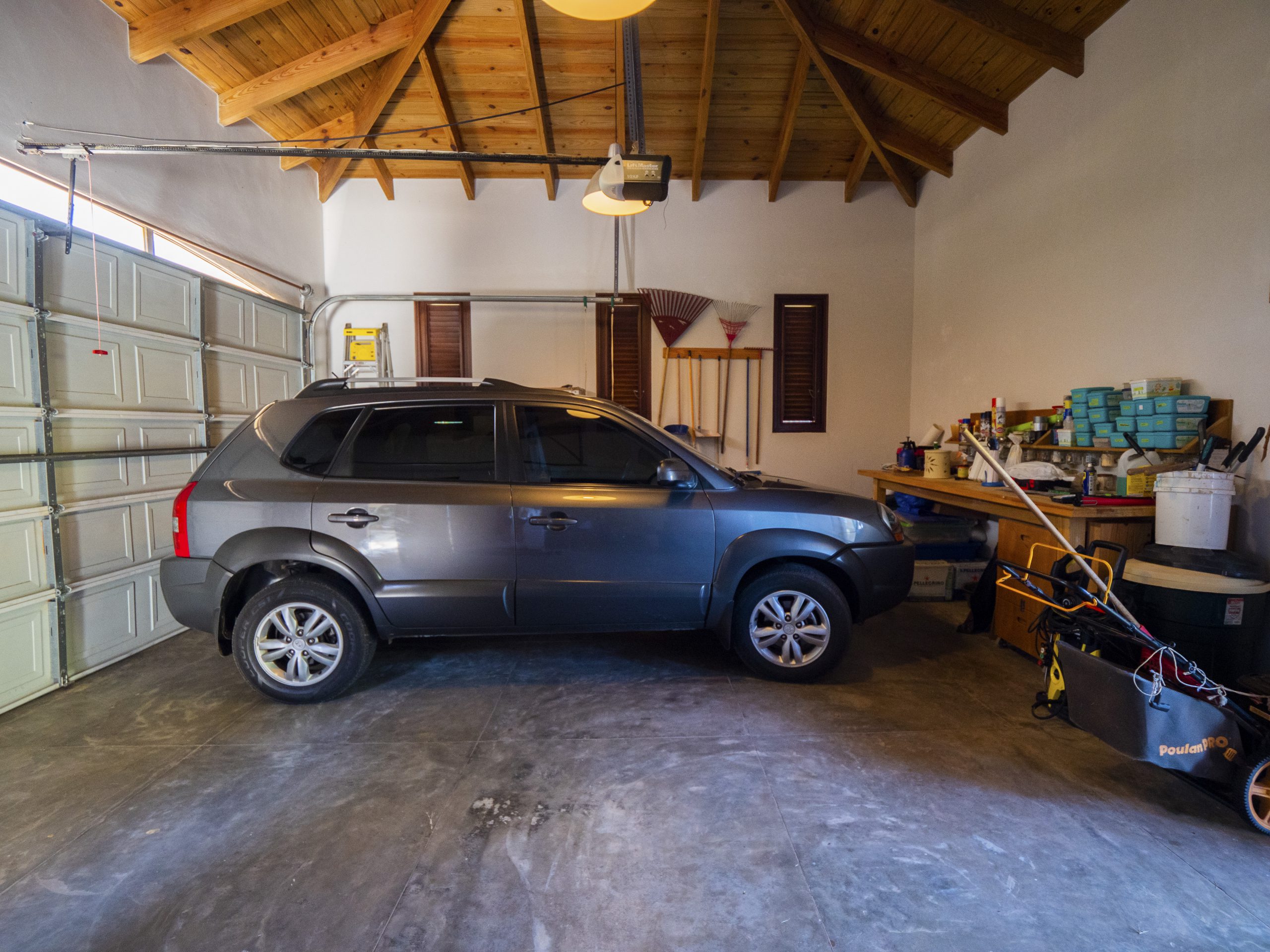 buyDRproperty Gray SUV parked inside a well-organized garage with wooden ceiling Sosua Real Estate