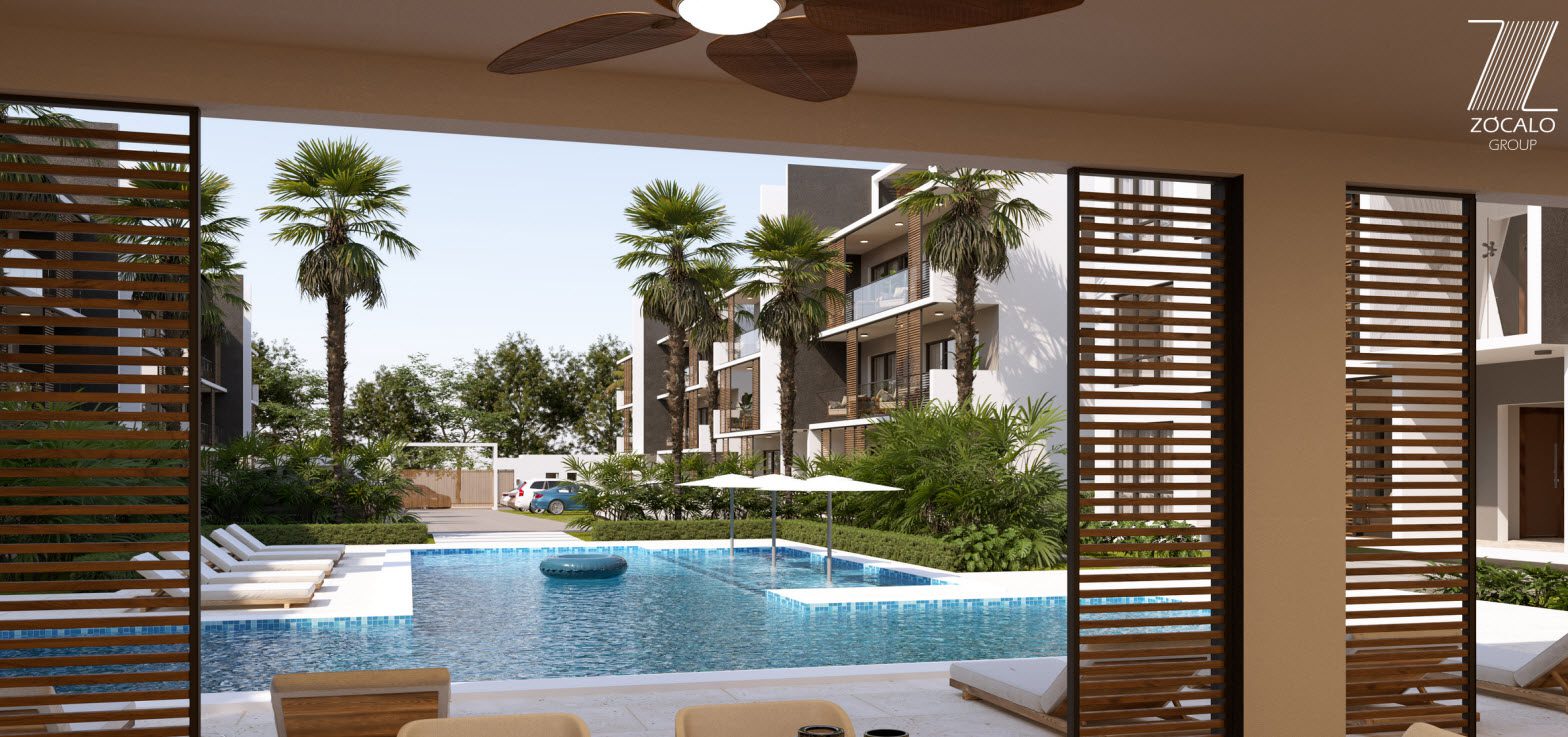 buyDRproperty Luxury resort pool with lounge chairs and palm trees, seen from a condo balcony. Zocalo Group logo visible. Sosua Real Estate
