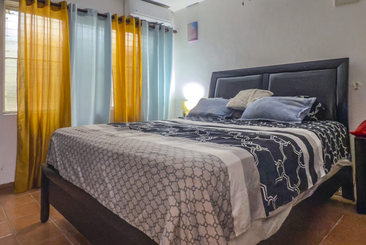 buyDRproperty Bedroom in Sosúa condo for sale, with bed, curtains, and tile floor. Close to playa. Sosua Real Estate