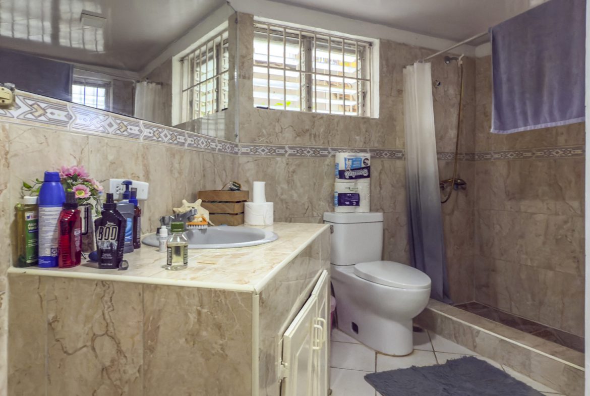 buyDRproperty Bathroom with beige tile, toilet, sink, and window in Sosúa. Near the playa! Sosua Real Estate