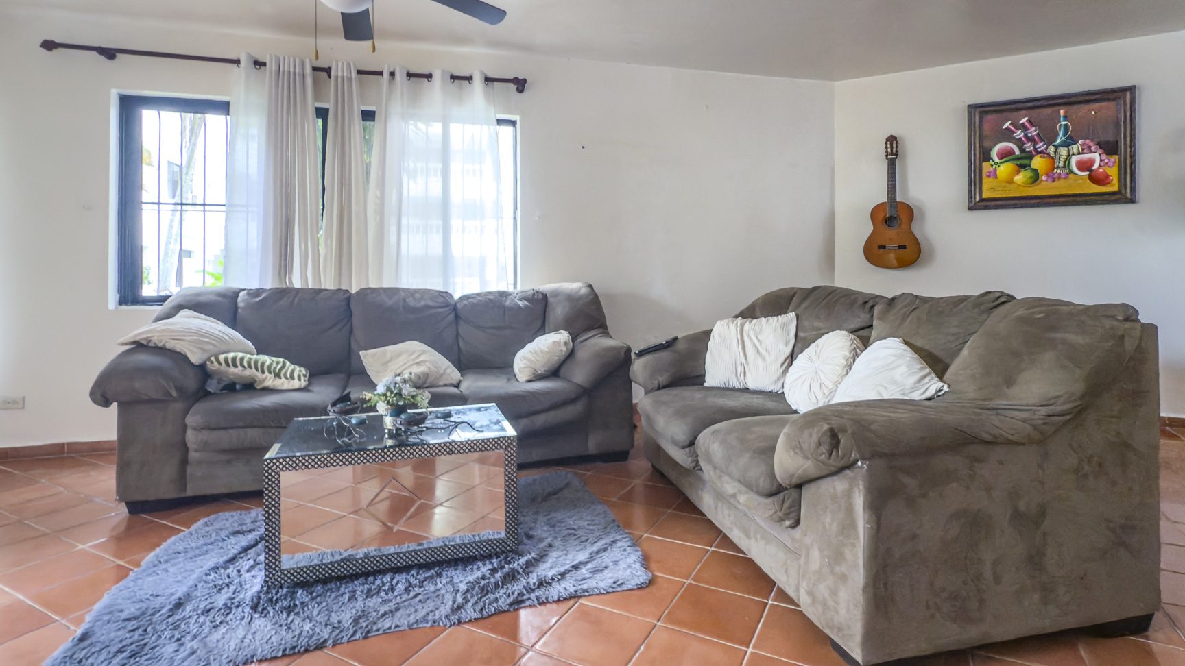 buyDRproperty Cozy living room with gray sofas, guitar on wall, and tiled floors. Great value in Sosúa. Sosua Real Estate