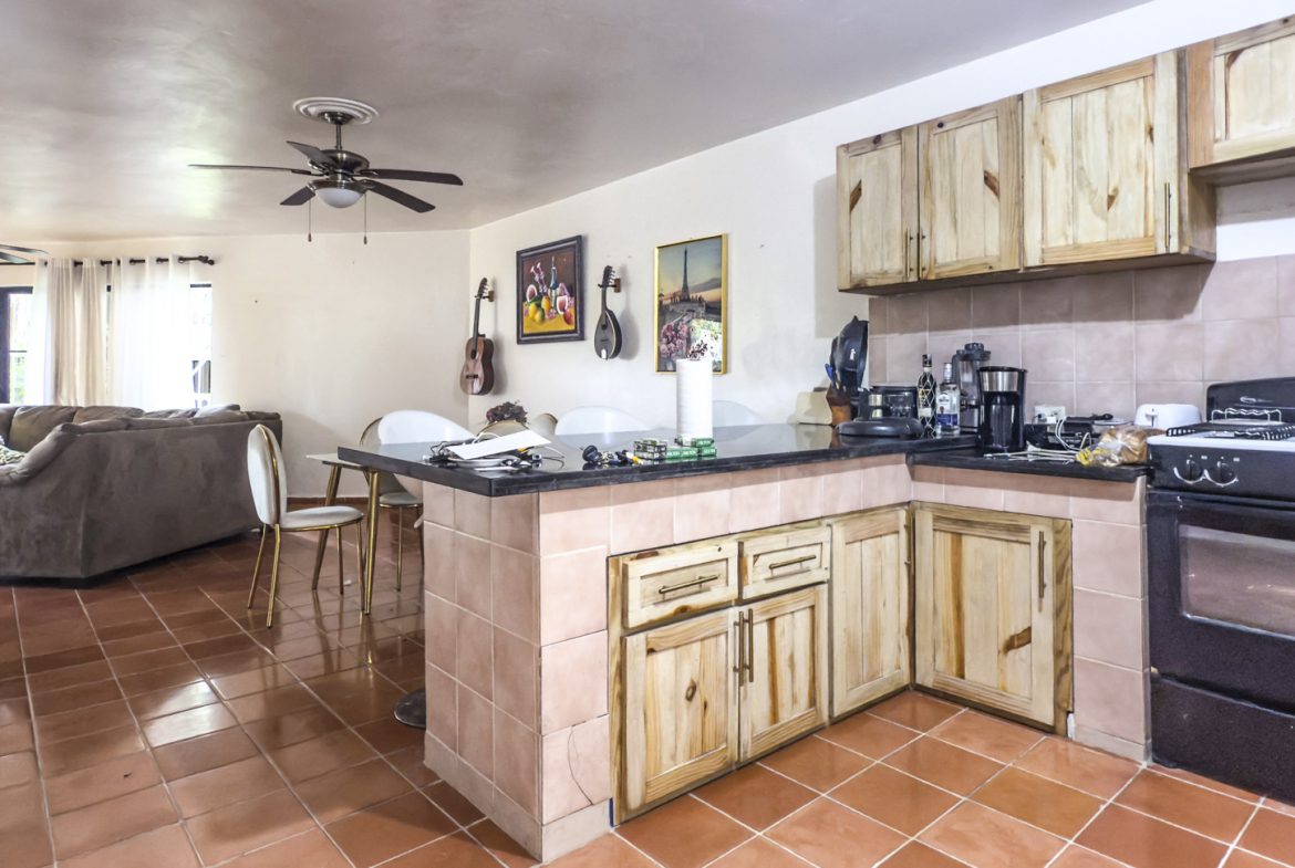buyDRproperty Open concept kitchen and living area in Sosúa home for sale, featuring tile flooring and wood cabinetry. Sosua Real Estate