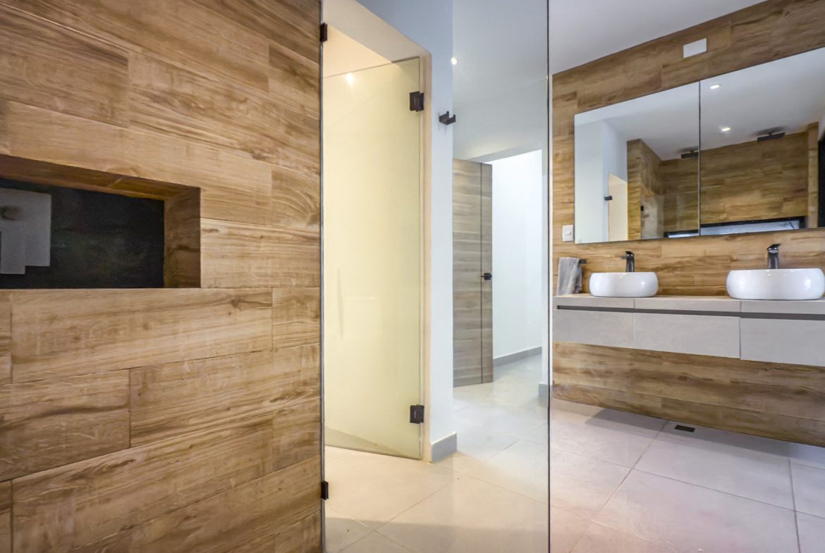 buyDRproperty Luxury bathroom in Sosua Ocean Village villa with wood paneling and double sinks. Sosua Real Estate
