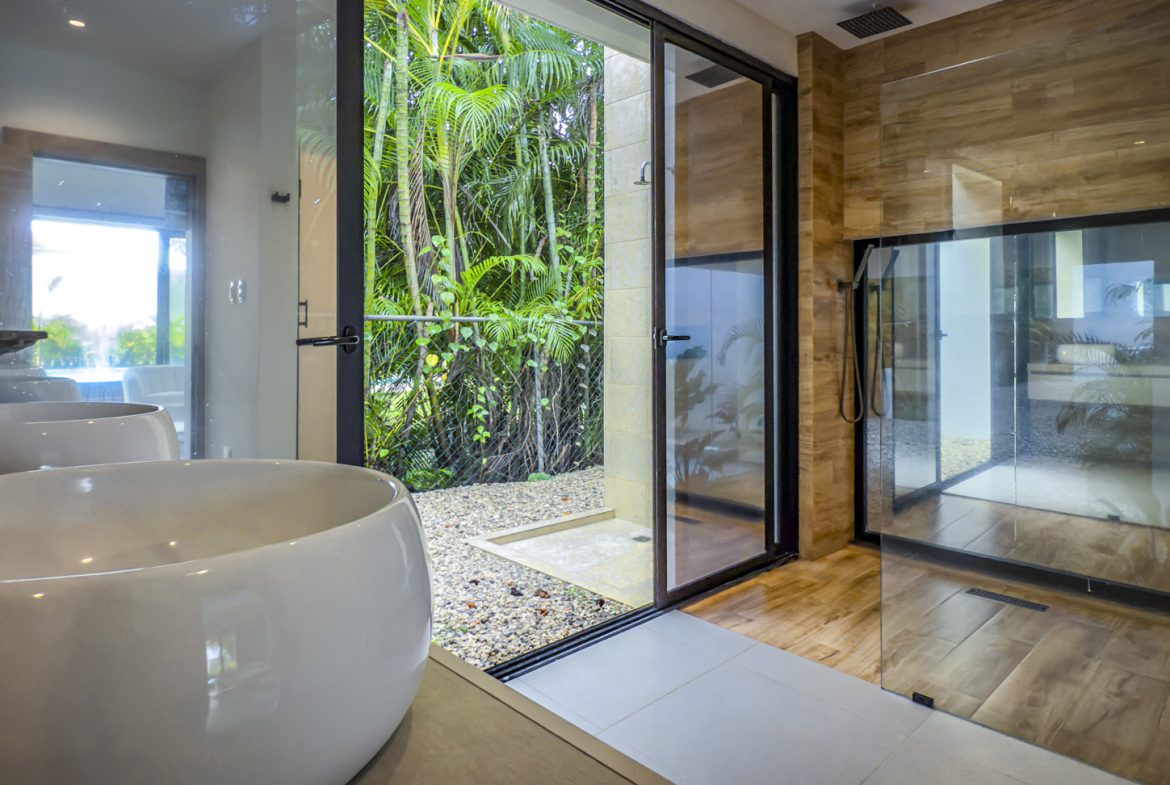 buyDRproperty Luxury bathroom with tub, open shower, and tropical garden view. Sosua Real Estate