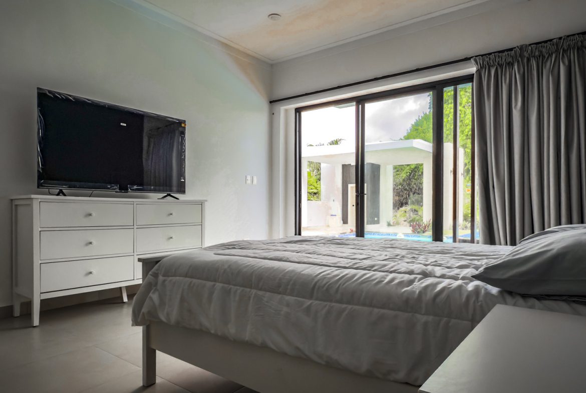 buyDRproperty Luxury bedroom with TV and sliding glass doors to a pool at Sosua Ocean Village. Sosua Real Estate