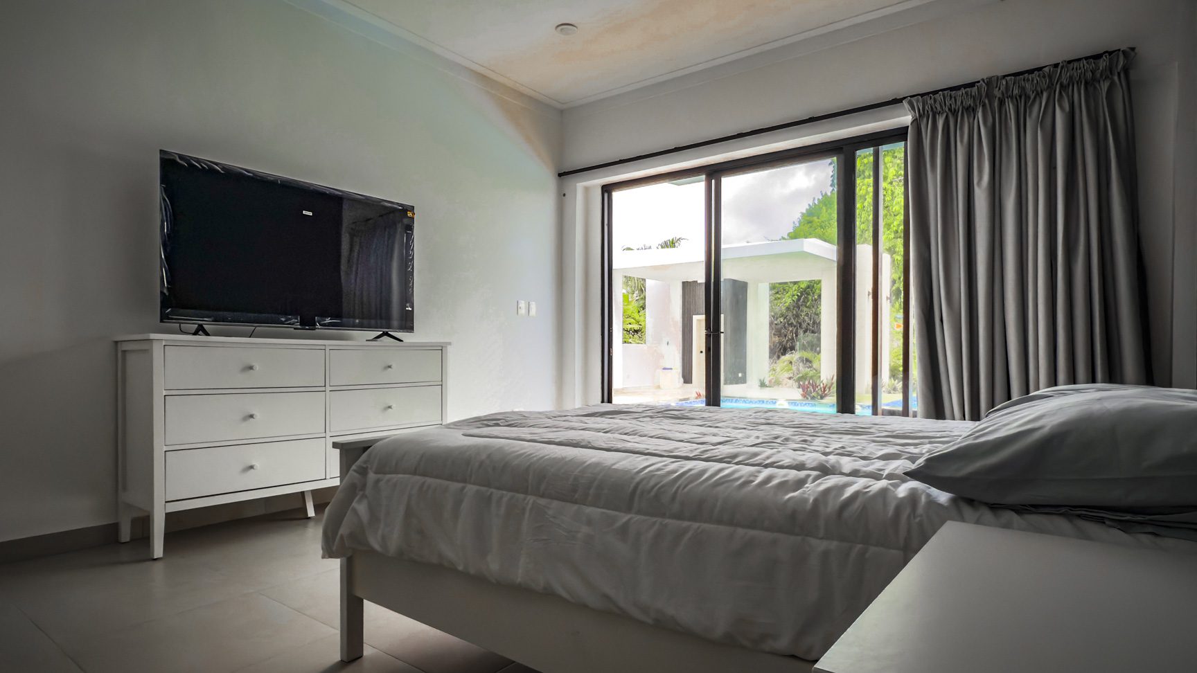 buyDRproperty Luxury bedroom with TV and sliding glass doors to a pool at Sosua Ocean Village. Sosua Real Estate