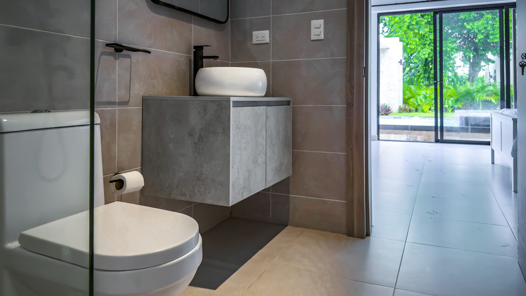 buyDRproperty Modern bathroom in a luxury villa with toilet, sink, and view to the garden. Sosua Real Estate