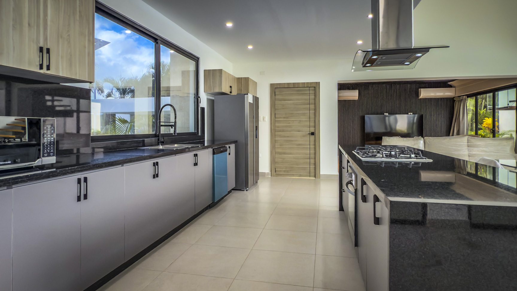 buyDRproperty Modern kitchen in a luxury Sosua Ocean Village villa, with black countertops and stainless steel appliances. Sosua Real Estate