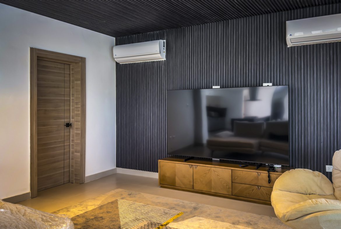 buyDRproperty Luxury villa interior with TV, modern wall paneling, and neutral tones in Sosua Ocean Village. Sosua Real Estate