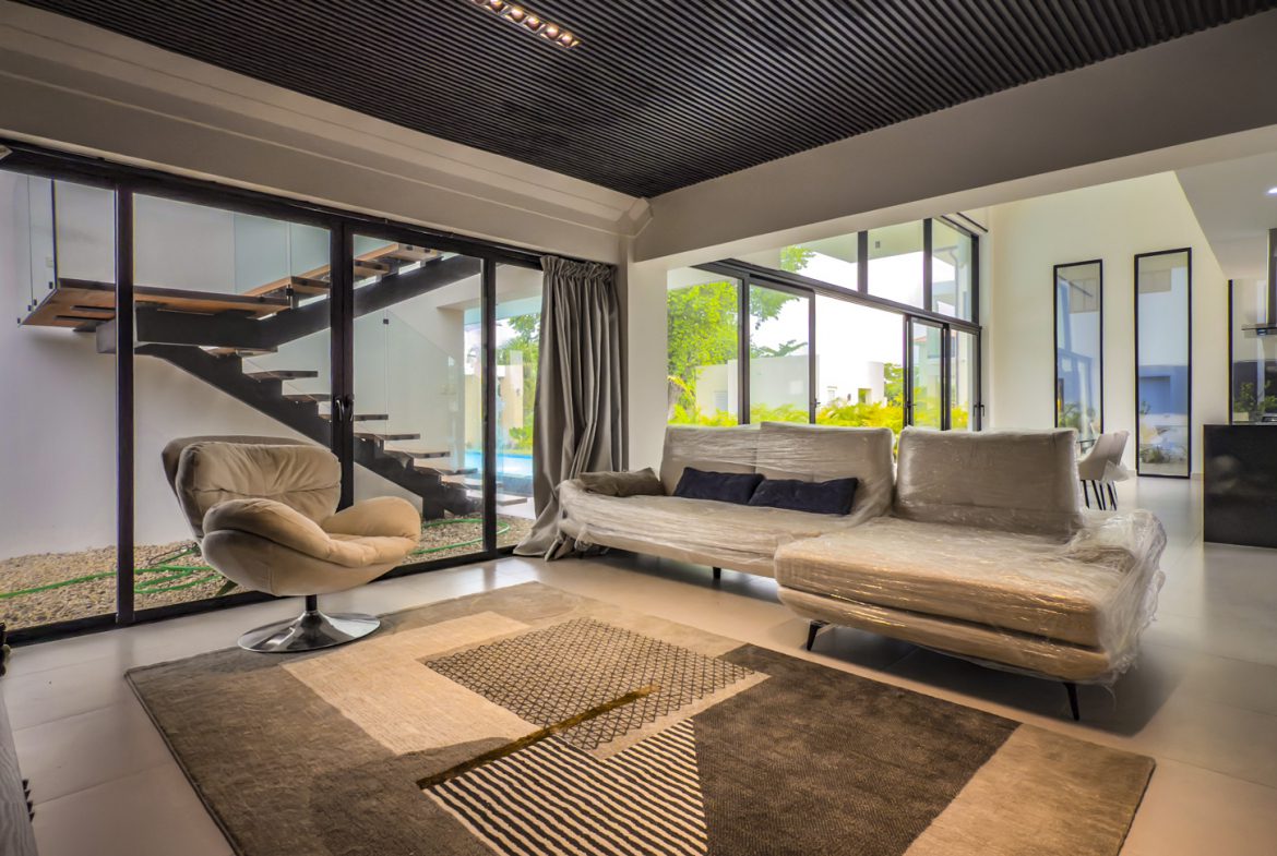 buyDRproperty Luxury villa interior with modern staircase, neutral tones, and large windows overlooking the pool. Sosua Real Estate