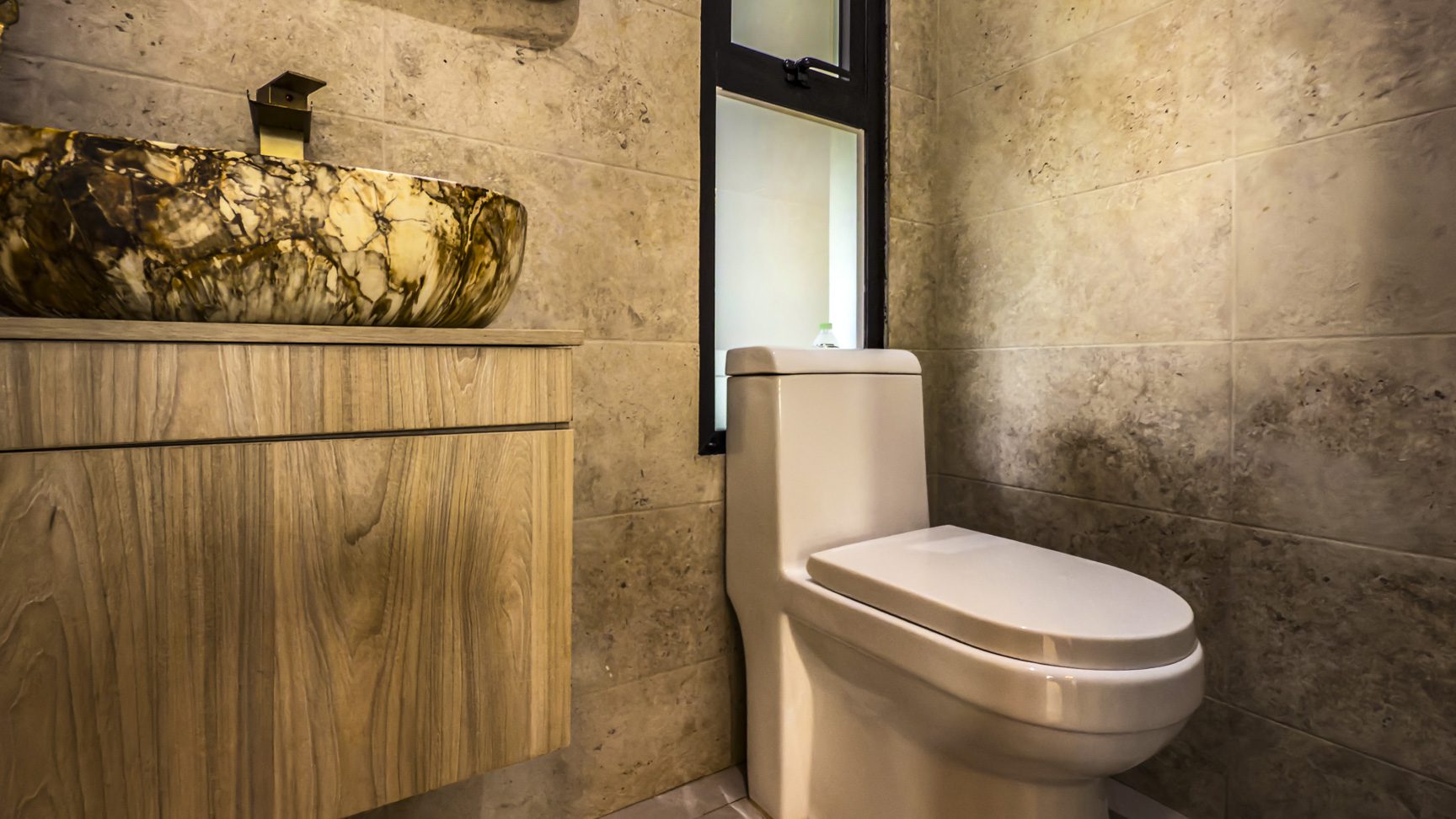buyDRproperty Luxury villa bathroom with stone vessel sink and modern toilet, tiled wall. Sosua Real Estate