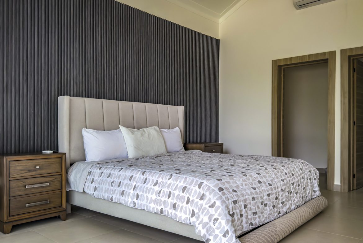 buyDRproperty Luxury bedroom in a Sosua villa with a grey and white patterned bedspread. Sosua Real Estate