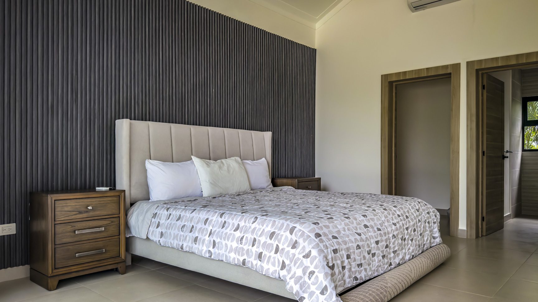 buyDRproperty Luxury bedroom in a Sosua villa with a grey and white patterned bedspread. Sosua Real Estate