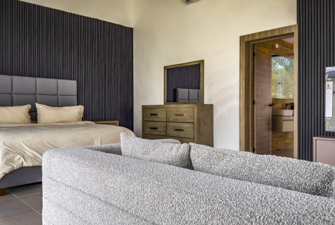buyDRproperty Luxury villa bedroom with bed, sofa, and dresser. Ocean Village property. Sosua Real Estate