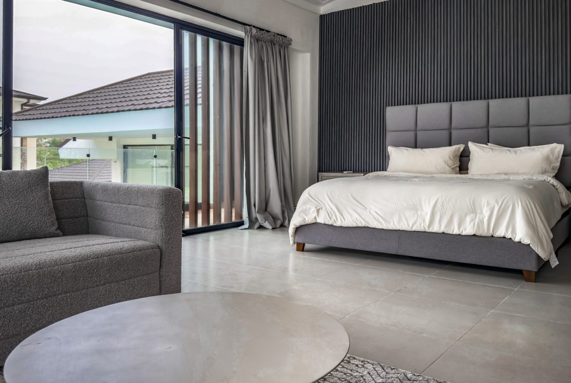 buyDRproperty Luxury bedroom in Sosua Ocean Village villa with gray decor, bed, and view of the villa exterior. Sosua Real Estate