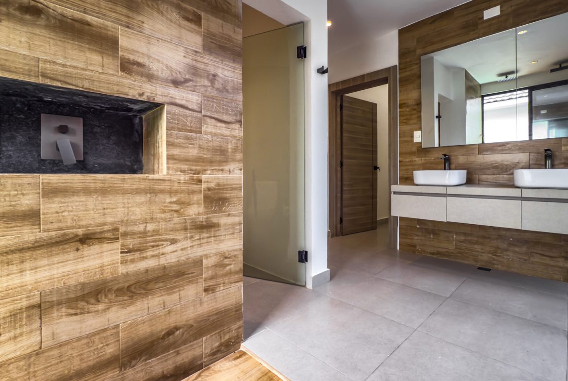 buyDRproperty Luxury bathroom with wood-look tile, double sinks, and a large mirror in Sosua Ocean Village. Sosua Real Estate