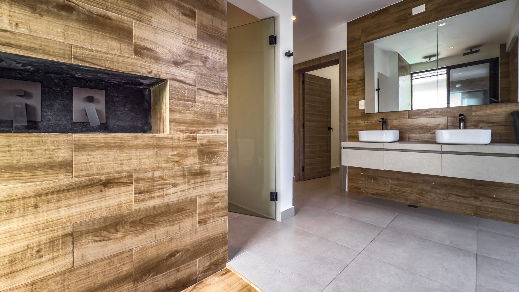 buyDRproperty Luxury bathroom with wood-look tile, double sinks, and a large mirror in Sosua Ocean Village. Sosua Real Estate