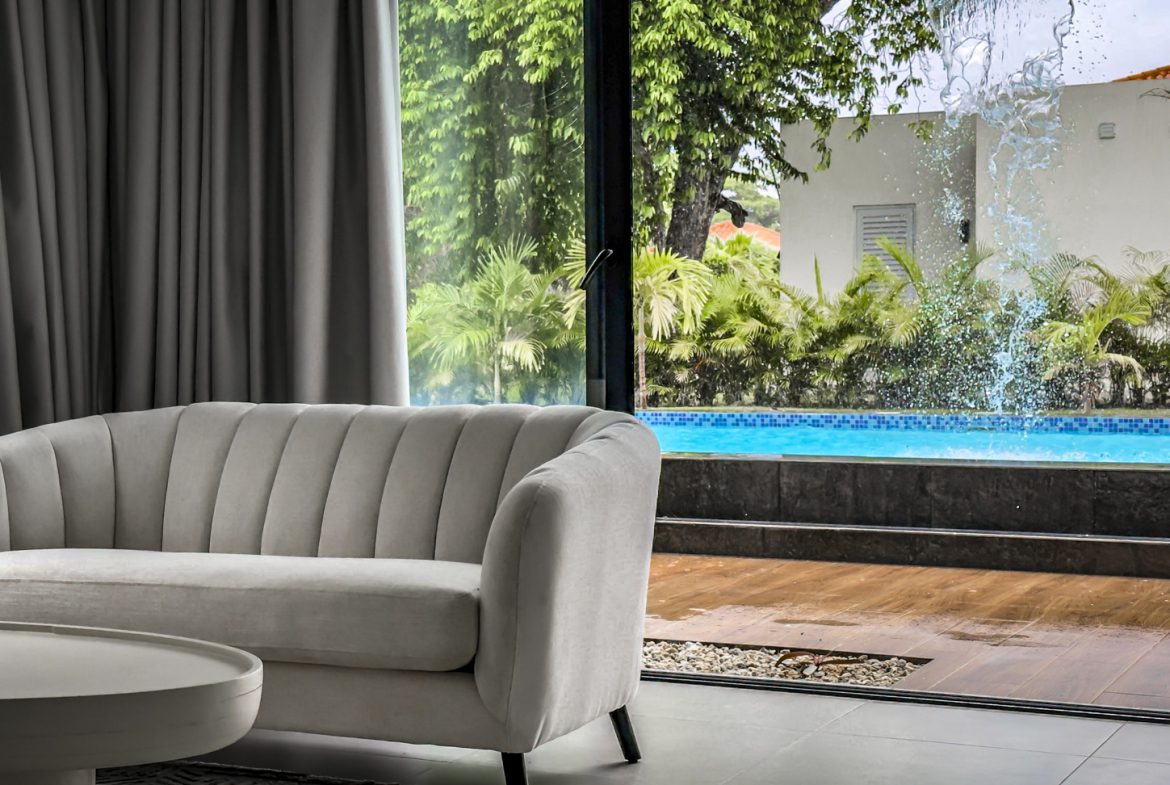 buyDRproperty Luxury villa interior with a modern sofa and pool view, Sosua Ocean Village. Sosua Real Estate