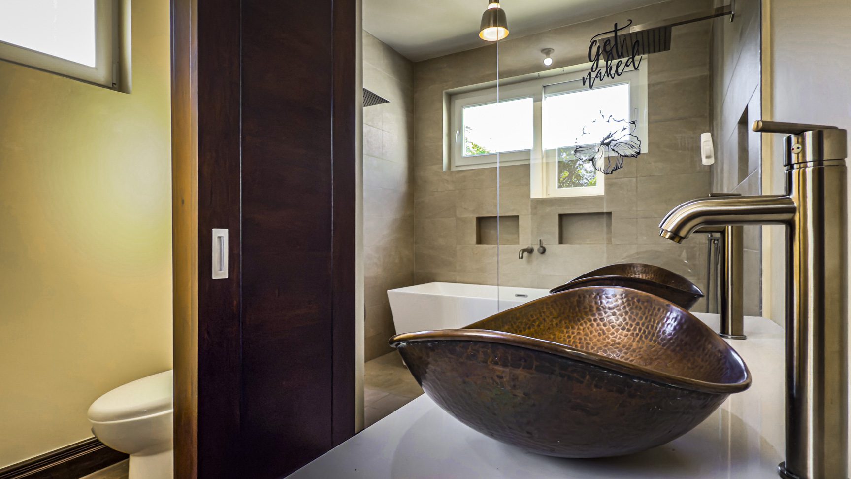 buyDRproperty Modern bathroom featuring a copper sink, glass shower, and a sliding barn door. Sosua Real Estate