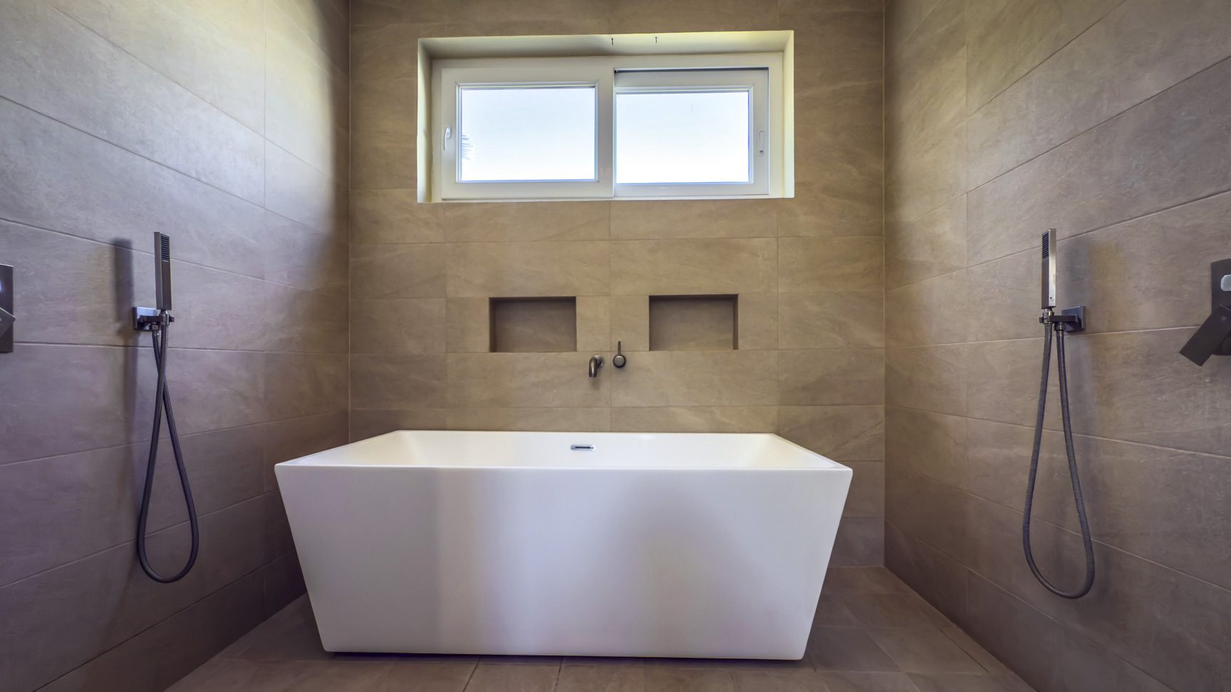 buyDRproperty Modern bathroom with white freestanding tub, neutral tile, and window. Sosua Real Estate