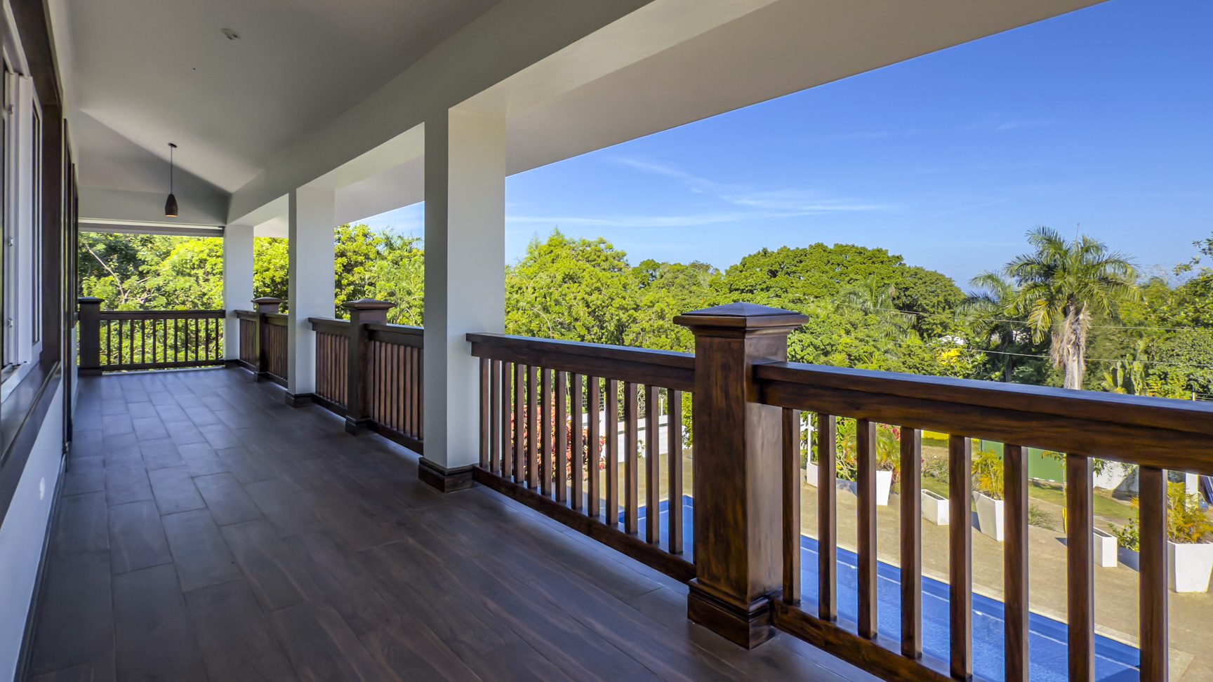 buyDRproperty Balcony view of La Mulata villa with wood railings and lush greenery. For Sale! Sosua Real Estate
