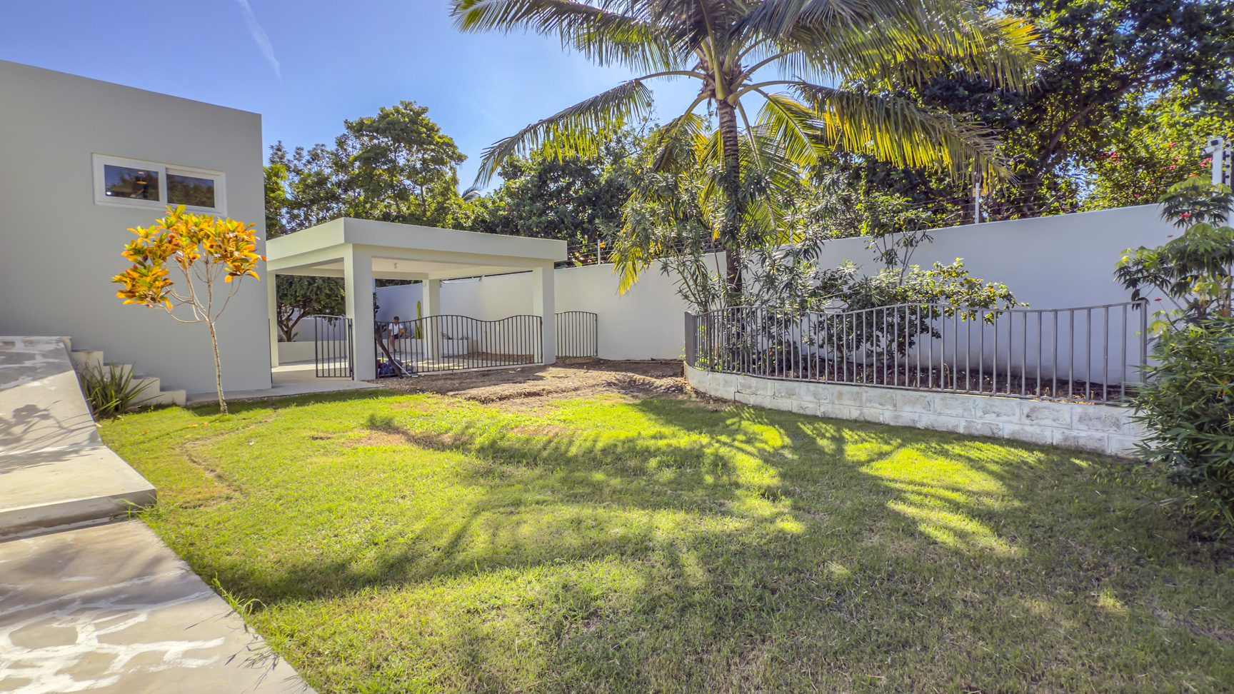 buyDRproperty La Mulata villa for sale: Backyard with lawn, patio, and tropical landscaping. Sosua Real Estate