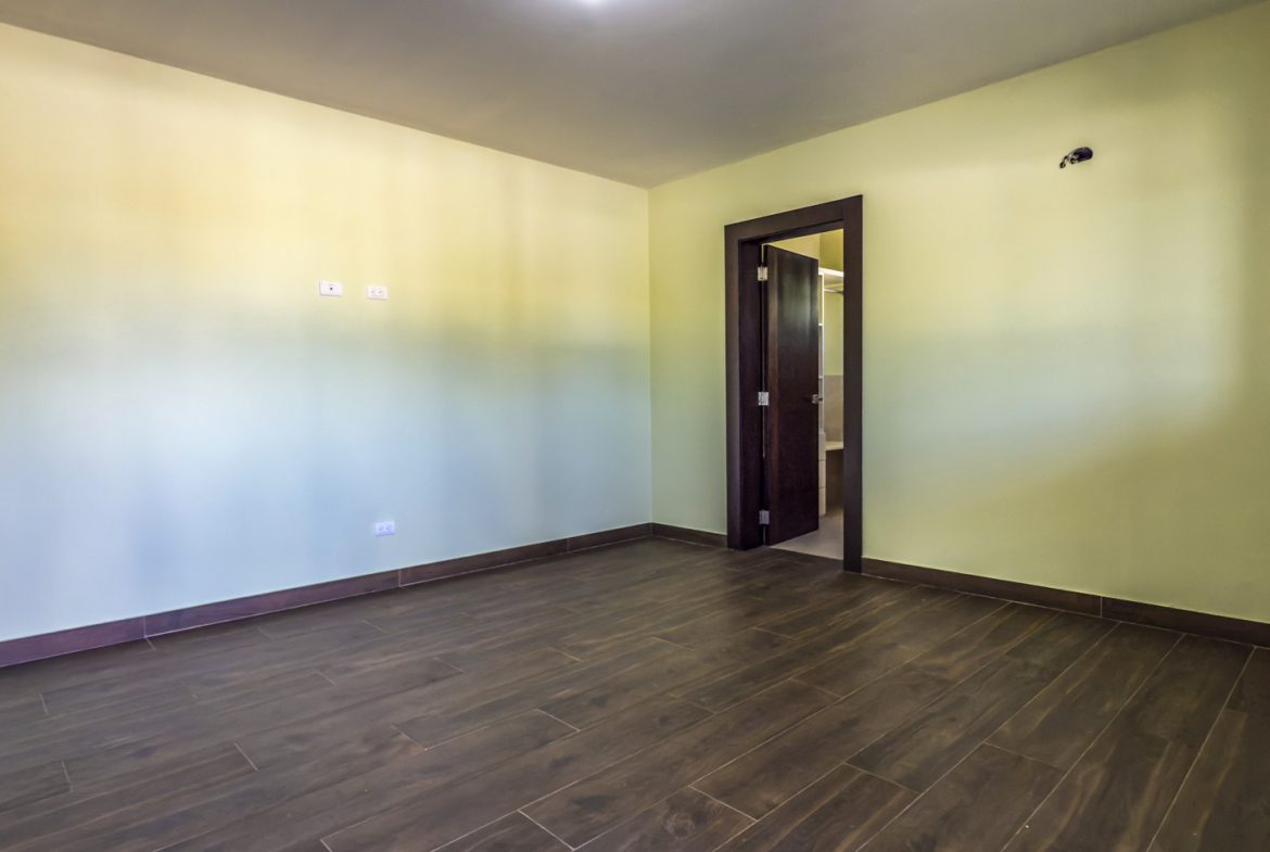 buyDRproperty Empty room in a 3-bedroom villa for sale in La Mulata with dark wood floors and a doorway to another room. Sosua Real Estate