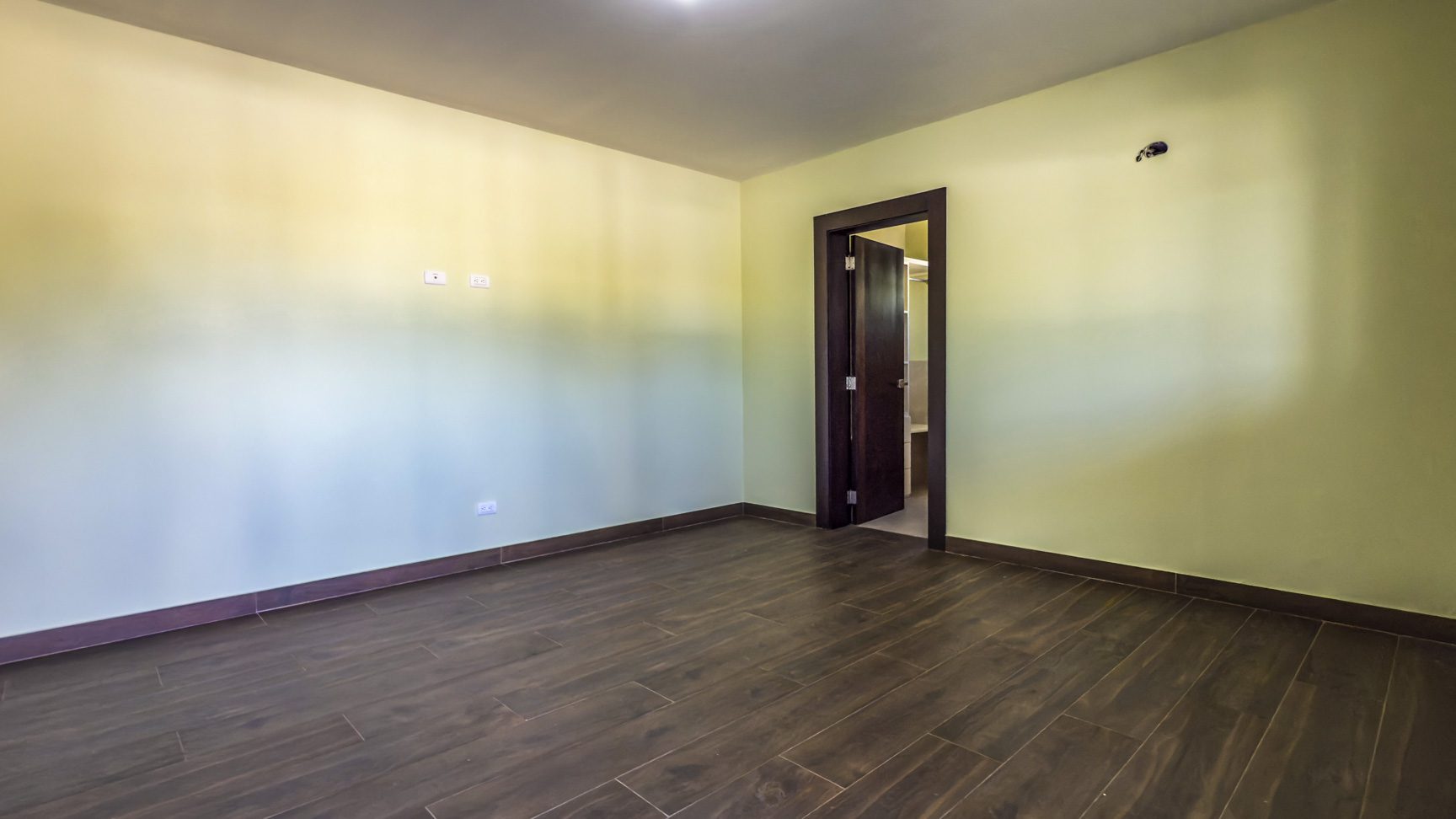 buyDRproperty Empty room in a 3-bedroom villa for sale in La Mulata with dark wood floors and a doorway to another room. Sosua Real Estate