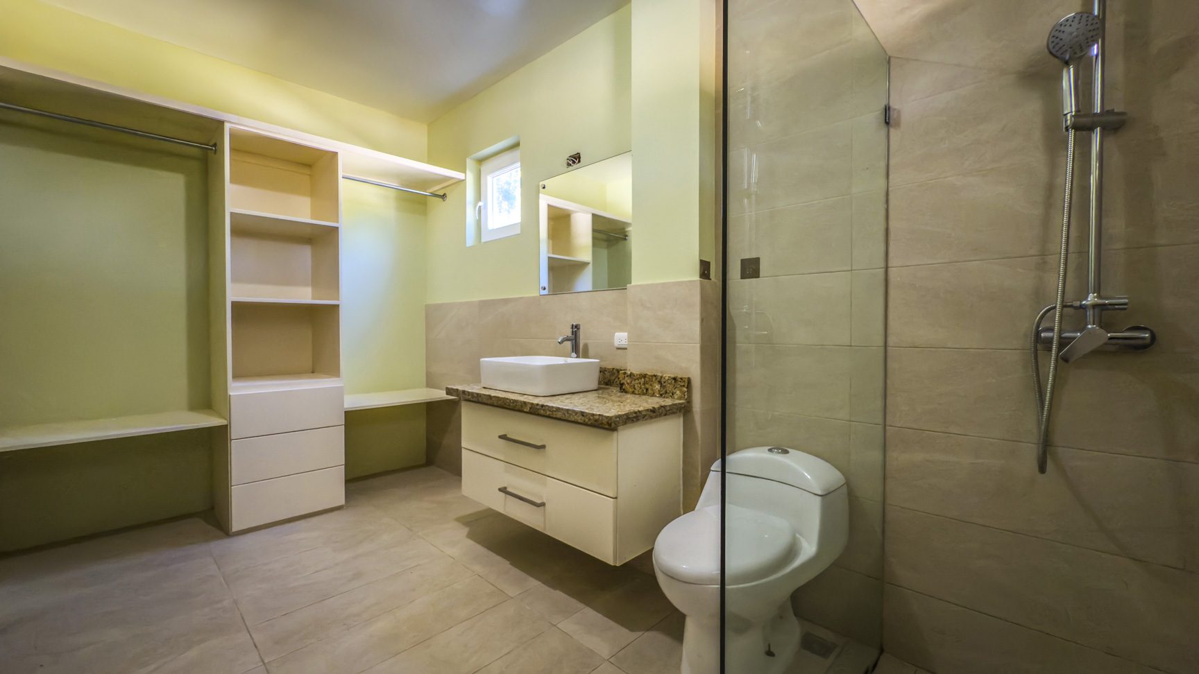 buyDRproperty Modern bathroom with shower, toilet, vanity, and open closet space in La Mulata villa. Sosua Real Estate